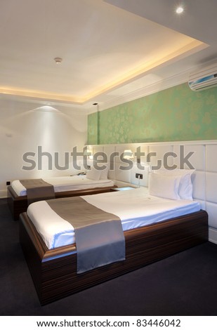 Interior of a hotel room for two, two beds and green wallpapers.