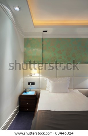 Interior of a hotel room for two, a bed and green wallpapers.
