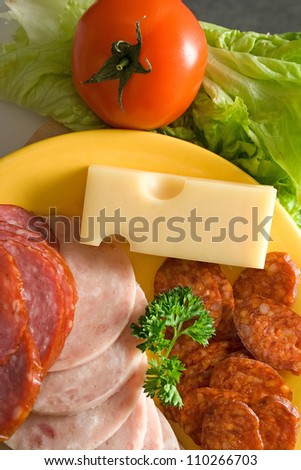 Top view of salami and sausage slices, cheese and vegetables