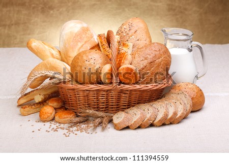 Different bread products with milk in jug on canvas