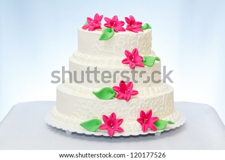 Three-storied white wedding cake with pink marzipan flower decoration