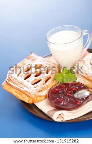 Macro of sour cherry cake, jam and milk on plate, blue background