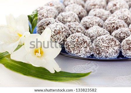 Closeup view of several snowball cake rolled in shredded coconut on blue plate with white flower