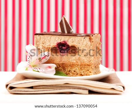 Slice of chocolate mousse cake in front of red-white striped background