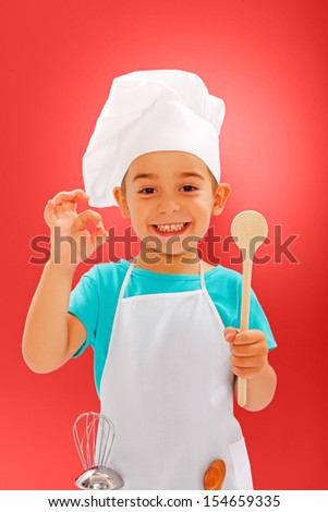 Cheerful little chef showing good taste and wooden spoon