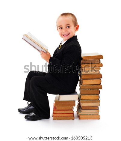 Portrait of a funny little kid sitting on old books and reading