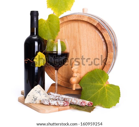 Red wine in bottle and glass with cheese and sausage snack in front of small barrel