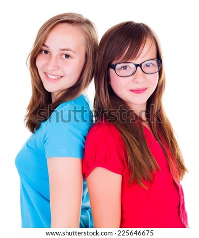 Two smiling teen girls standing back-to-back on white