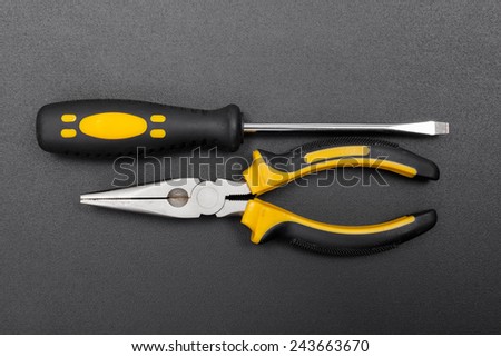 Electrician tools: pliers and screwdriver on black