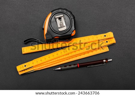 Measuring tape, ruler tool and pencil on black