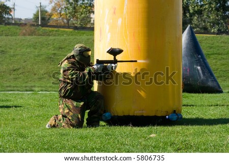 Paintball player aiming and shooting with marker