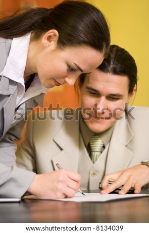 Woman signs a document in front of a men