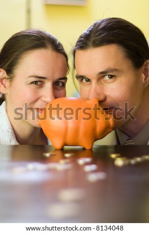 Couple behind piggy bank and some coins in front