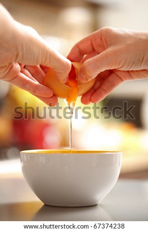 Food preparing, back view of hands cracking up a raw egg