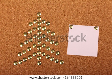 Thumb tacks in shape of Christmas tree on cork board