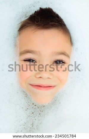 Seven years boy in a bubble bath filled with soap foam