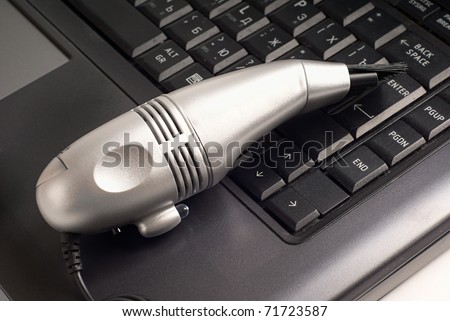Small silver vacuum cleaner on laptop keyboard