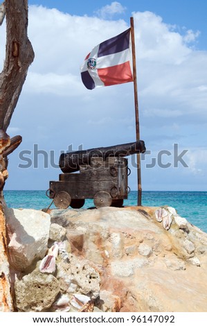 old cast-iron cannon, and the ship anchor in front of of the flag of the Dominican Republic on the Atlantic coast