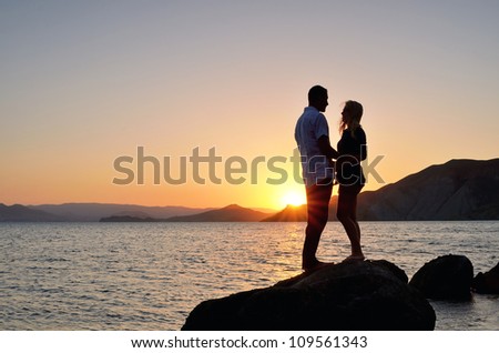 Young couple talking on the beach with the setting sun