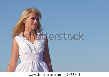 Blonde in a white dress on a background of blue sky