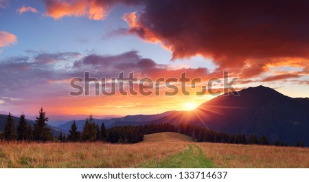 Panorama of the mountains with a beautiful sunset and the sun with rays