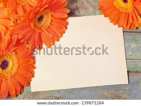 Sheet of paper for notes on a wooden board surrounded by orange flowers