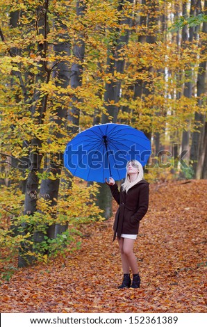 Woman with the blue umbrella in the autumn park