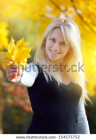 Blonde in a park holding a bouquet of autumn leaves