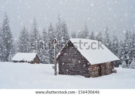 Winter landscape with a wooden hut in the mountains and the Orthodox cross. Ukraine, Carpathian Mountains