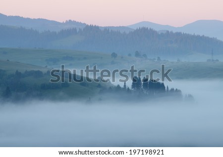 Morning landscape with fog in the hills. Mountain village in the morning twilight. Carpathians, Ukraine