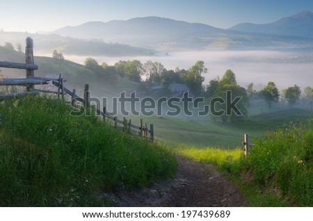 Morning landscape with a road in the mountain village. Sunny morning with fog over the settlement. Carpathian mountains, Ukraine, Europe