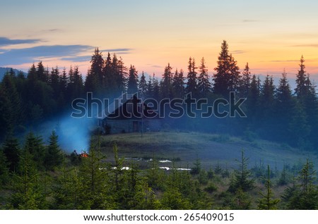 Summer evening. Mountain landscape. Camping in nature. Bonfire near the house
