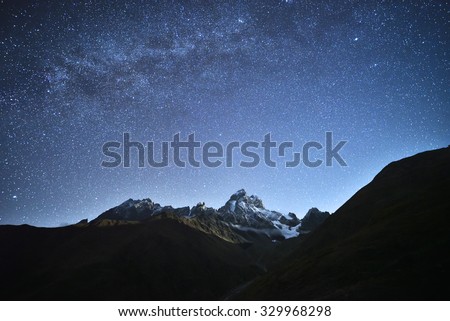 Night landscape. Starry sky with the Milky Way over the mountains. Mount Ushba in the light of the rising moon. Main Caucasian ridge. Zemo Svaneti, Georgia