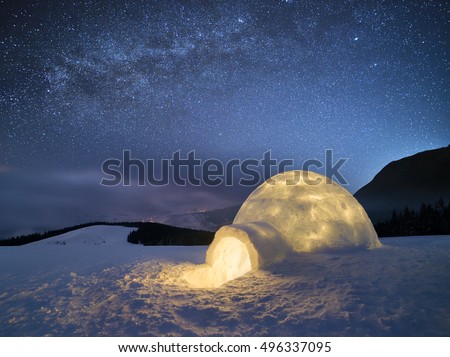 Night landscape with a snow igloo with light. Extreme house. Winter in the mountains. Sky with the stars and the Milky Way
