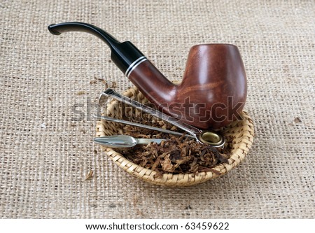 Tobacco pipe on sacking background with tobacco and accessory