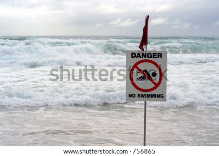 Warning sign with stormy ocean behind.