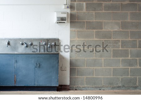 A grungy, dirty, industrial interior with concrete block walls and an old grubby sink system.