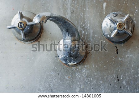 close up of a tap set set in a stainless steel sink or trough. Colourfully grungy and disgusting. Actually shot in an art classroom