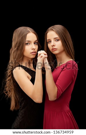 Portrait of two women holding hands on a black background
