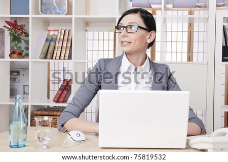Closeup portrait of cute young business woman at her workplace in an office environment