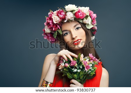 Portrait of beautiful smiling woman with a crown on his head and a bunch of flowers on a dark background in the studio. The concept of friendly spring.