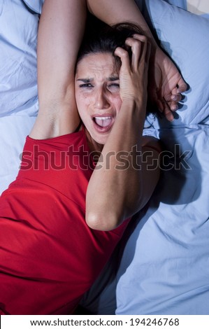 A battered woman on the bed crying and desperate attempts to defend himself with his own hands and arms while someone hits it with slaps and punches