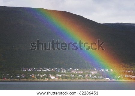 Beautiful rainbow across a fjord in Norway close to Tromsoe. Reflections on the water and copy space