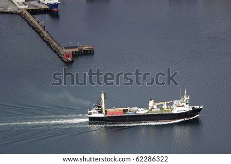 Norwegian black cargo ship sailing in the norwegian fjords.