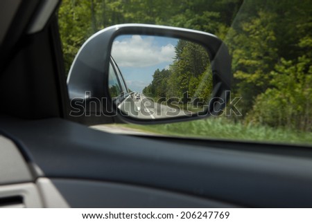 Rear view mirror, highway traffic visible.