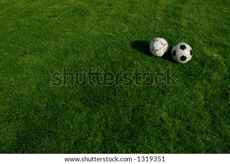 Two soccer balls on green grass