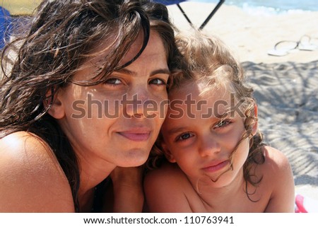 Portrait of mother and daughter smiling at the camera on the seaside