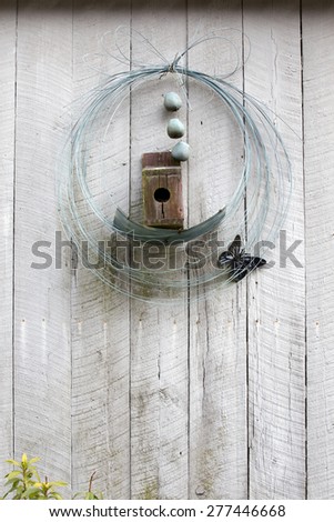 Old vintage birdhouse and garden decor with wire and metal butterfly hanging on a wall or fence with lots of copy space.