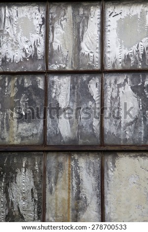 Vertical photo of old weathered rusted window boarded up with chipped and cracked grey panel