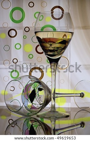 Two wine glasses in front of green, brown, and yellow circled abstract background